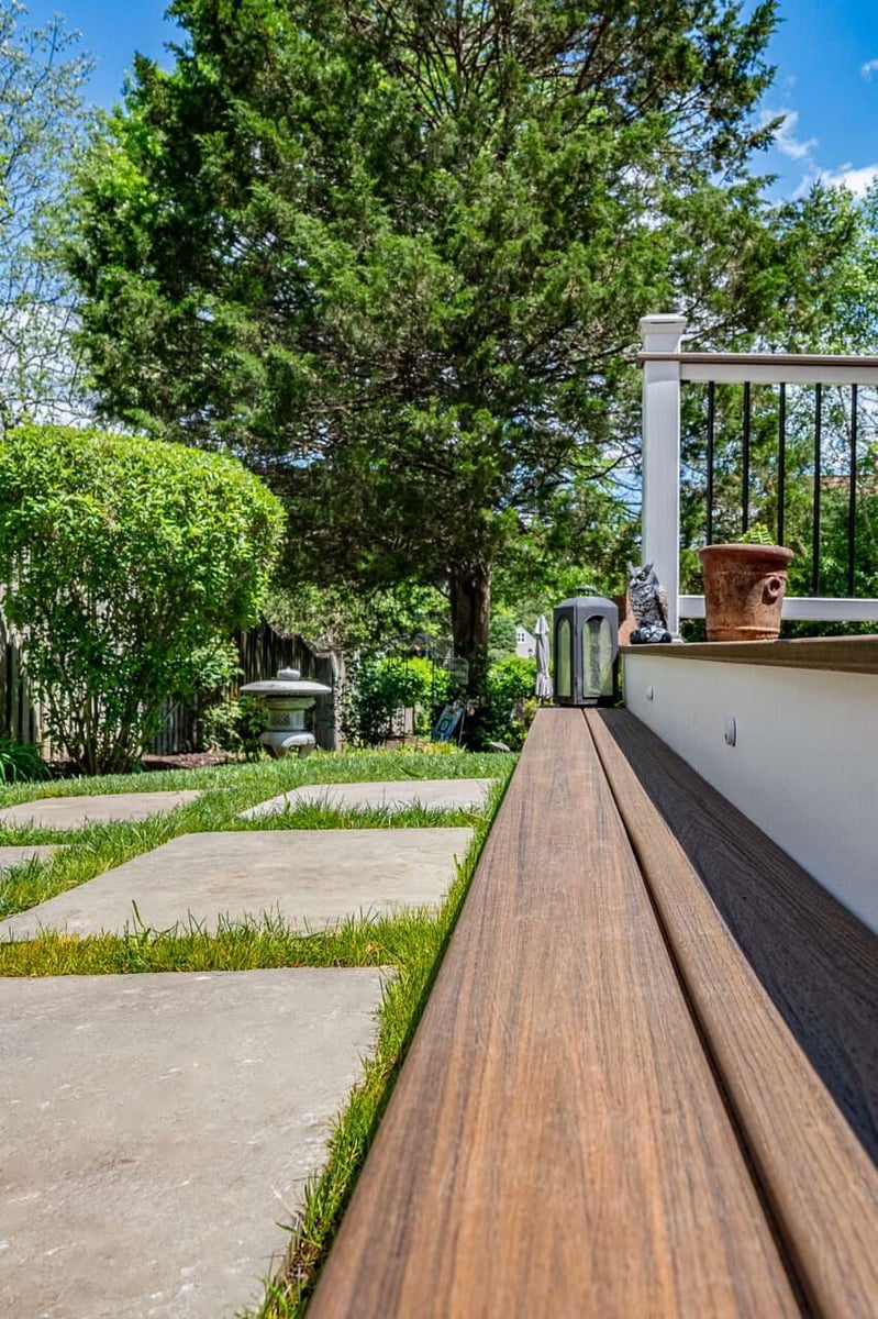 Low-profile Trex composite decking detail in Alexandria, VA adjacent to a modern stone paver walkway and landscaped lawn.