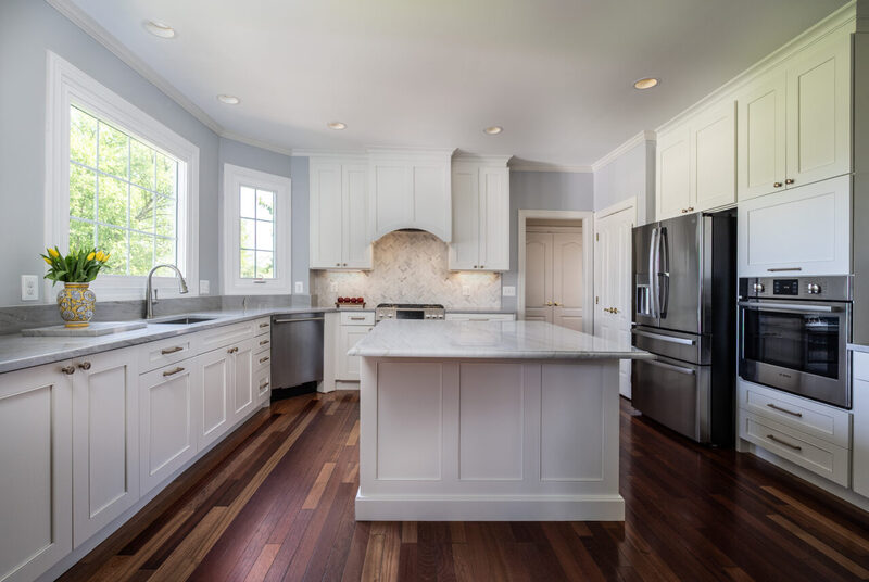 Open-concept kitchen remodel in Leesburg, VA featuring a spacious island with quartz countertops, stainless steel appliances, white shaker cabinetry, and hardwood floors.
