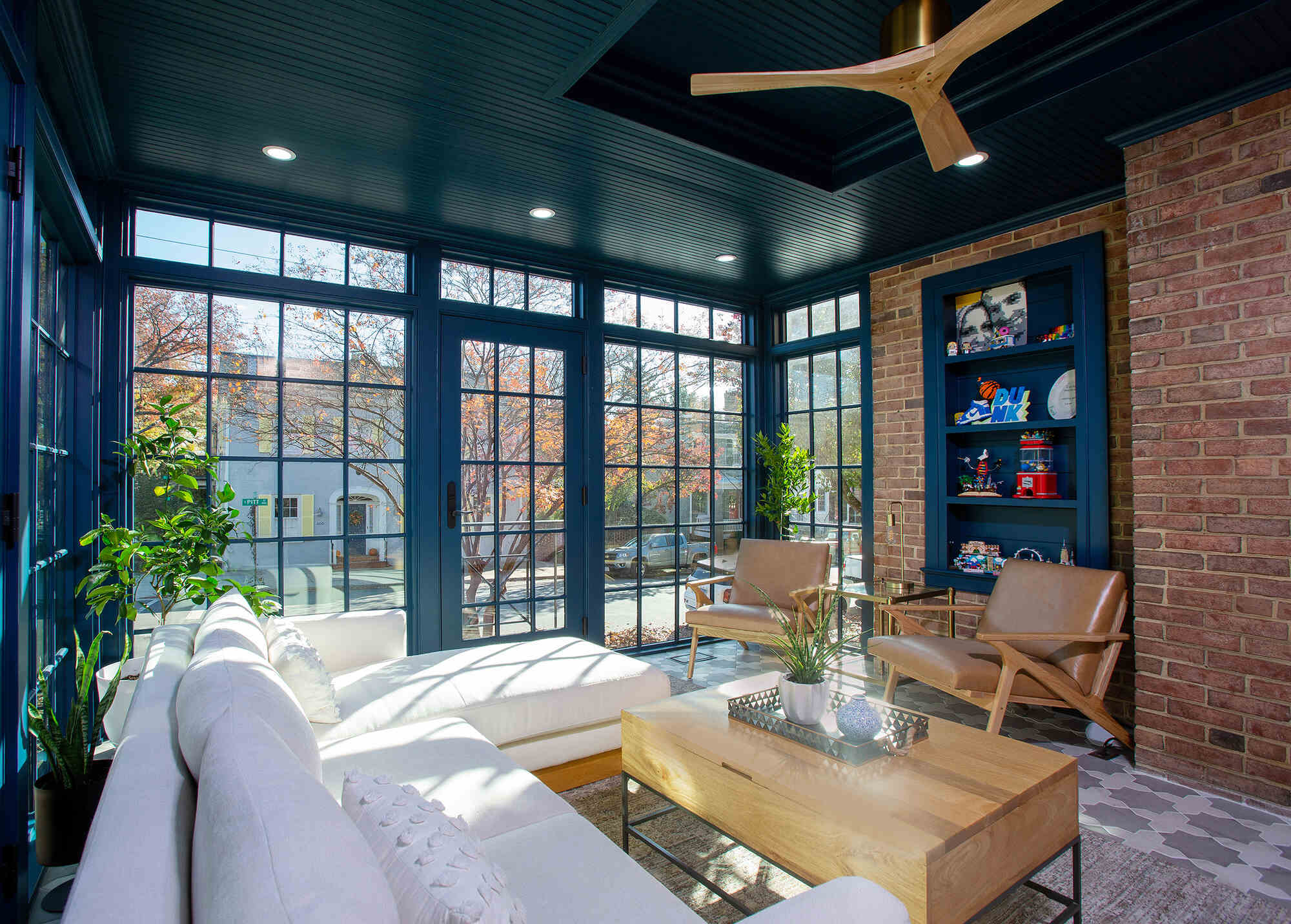 Interior of custom sunroom with navy grid windows and wood ceiling fan by Anchor Remodel in Alexandria, VA