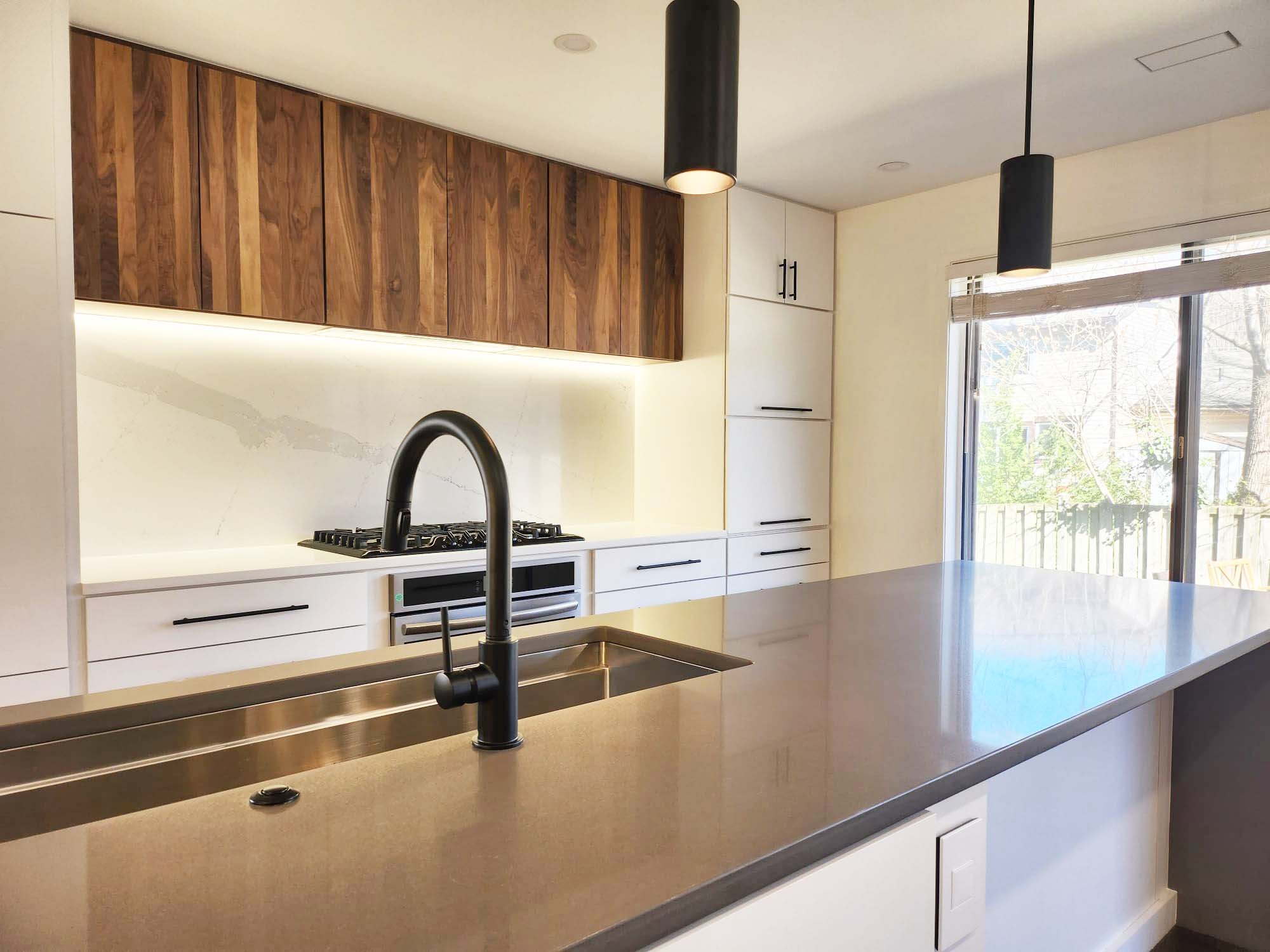 Stylish kitchen featuring pendant lighting and wide quartz island by Anchor Remodel in Alexandria, VA.