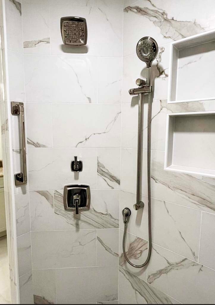 Close-up of custom shower fixtures and marble tile work by Anchor Remodel in McLean, VA.