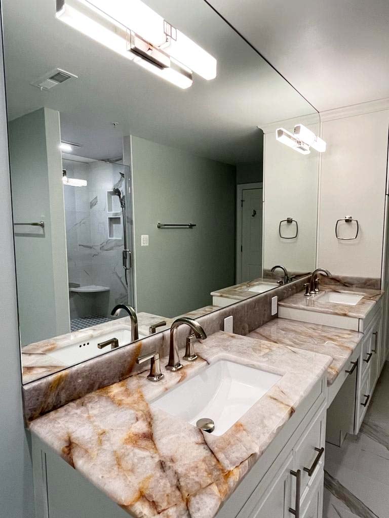 Dual sink vanity with natural stone countertop in a custom bathroom by Anchor Remodel in McLean, VA.