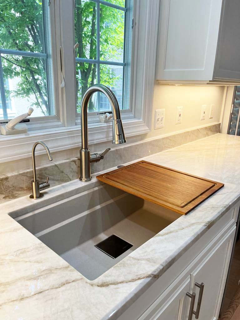 Elegant sink area with built-in cutting board and quartzite surface by Anchor Remodel in McLean, VA.