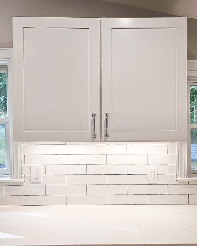 White upper kitchen cabinets with modern chrome pulls and subway tile backsplash by Anchor Remodel in Alexandria, VA.
