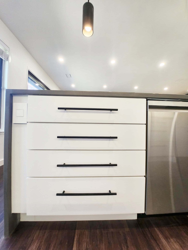 Close-up of modern kitchen drawers with black handles and seamless finish by Anchor Remodel in Alexandria, VA.