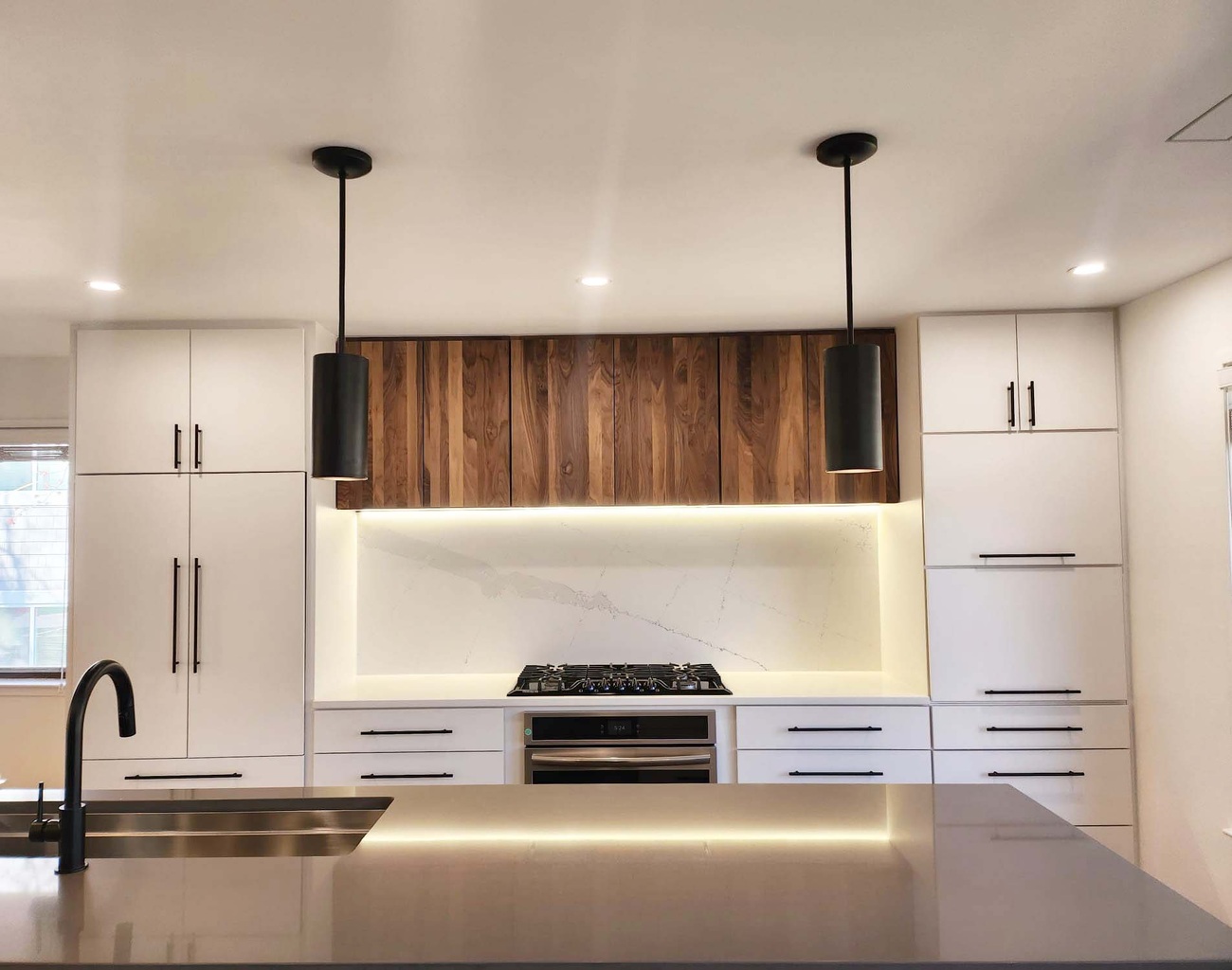Full view of kitchen with walnut cabinets and LED-lit backsplash by Anchor Remodel in Alexandria, VA.