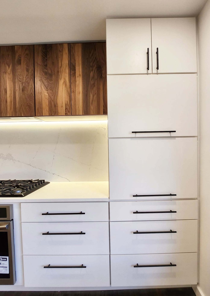 White flat panel cabinetry with black hardware and wood upper cabinets by Anchor Remodel in Alexandria, VA.