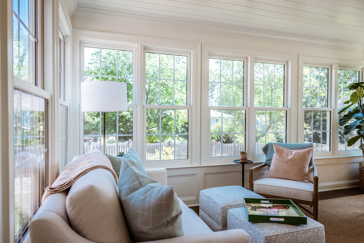 Relaxing corner with ottomans and windows in sunroom by Anchor Remodel in Alexandria, VA