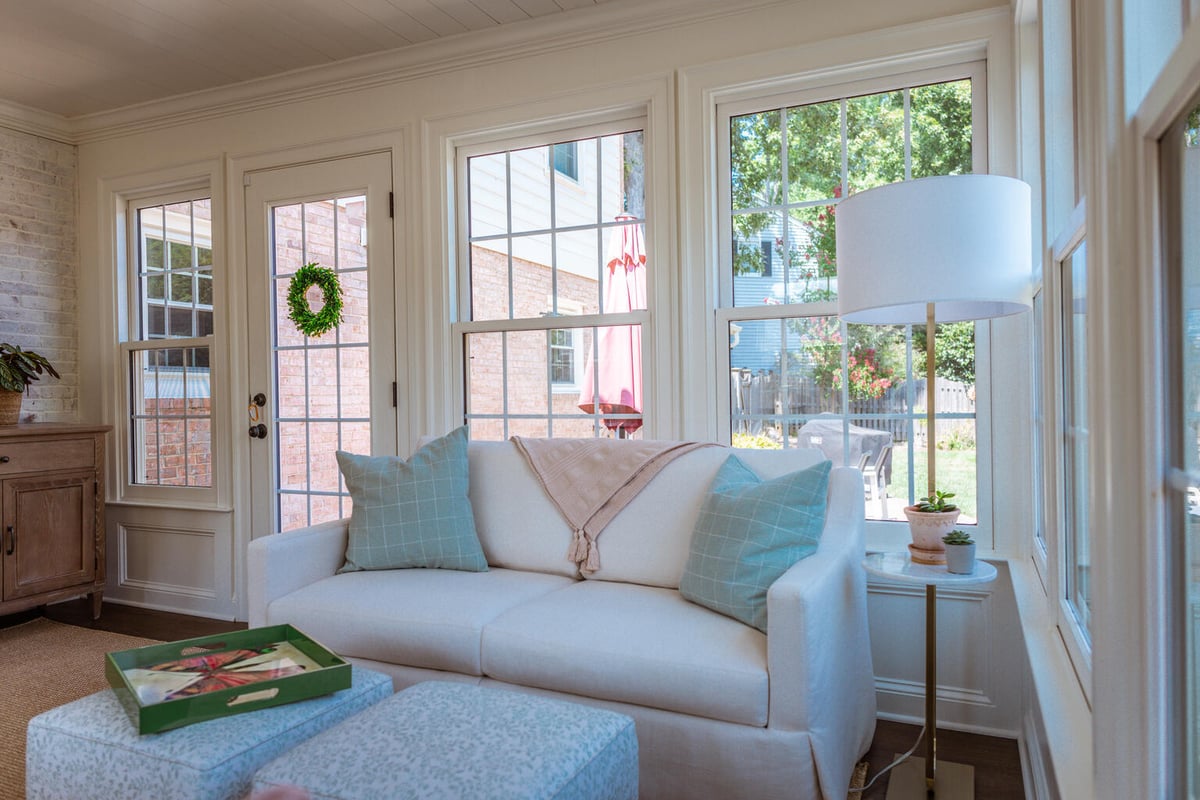 White sofa and window views in custom sunroom built by Anchor Remodel in Alexandria, VA