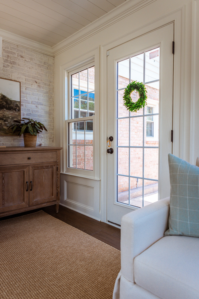 White-framed sunroom entrance with wreath and natural lighting by Anchor Remodel in Alexandria, VA