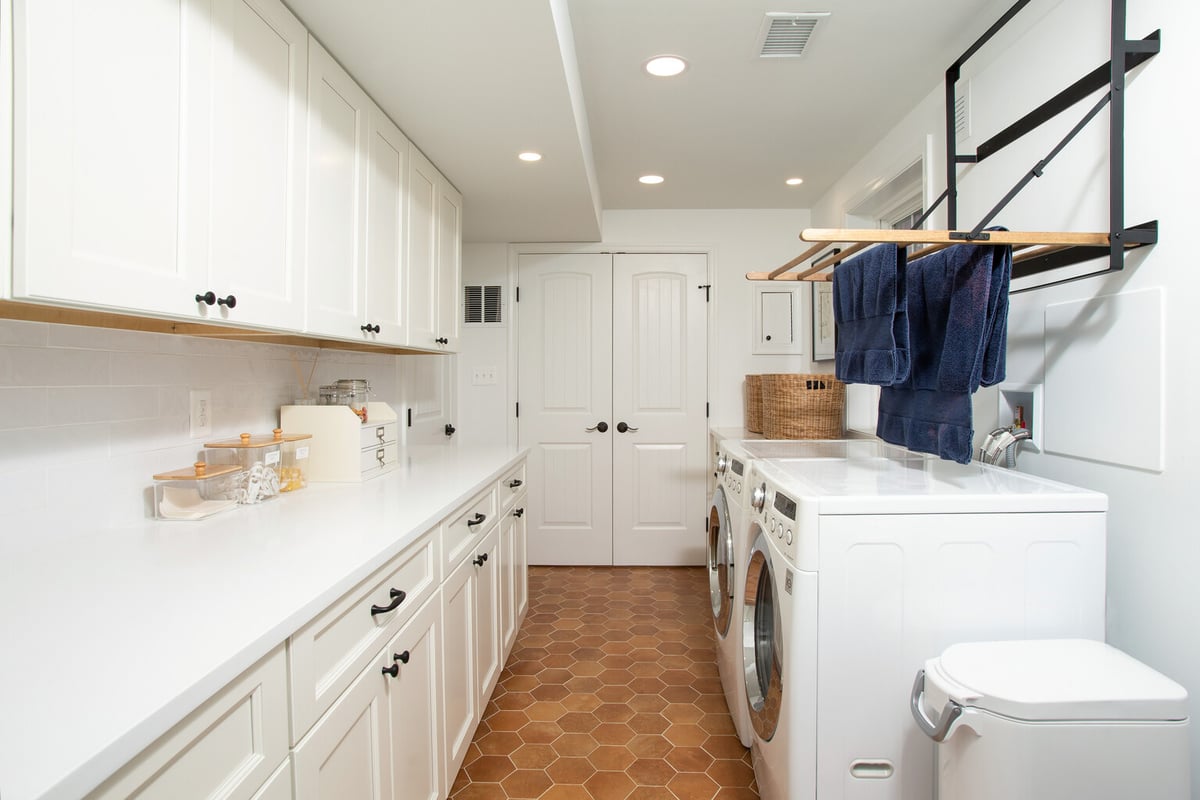 Sleek laundry space with drying rack and white cabinets by Anchor Remodel in Vienna, VA.