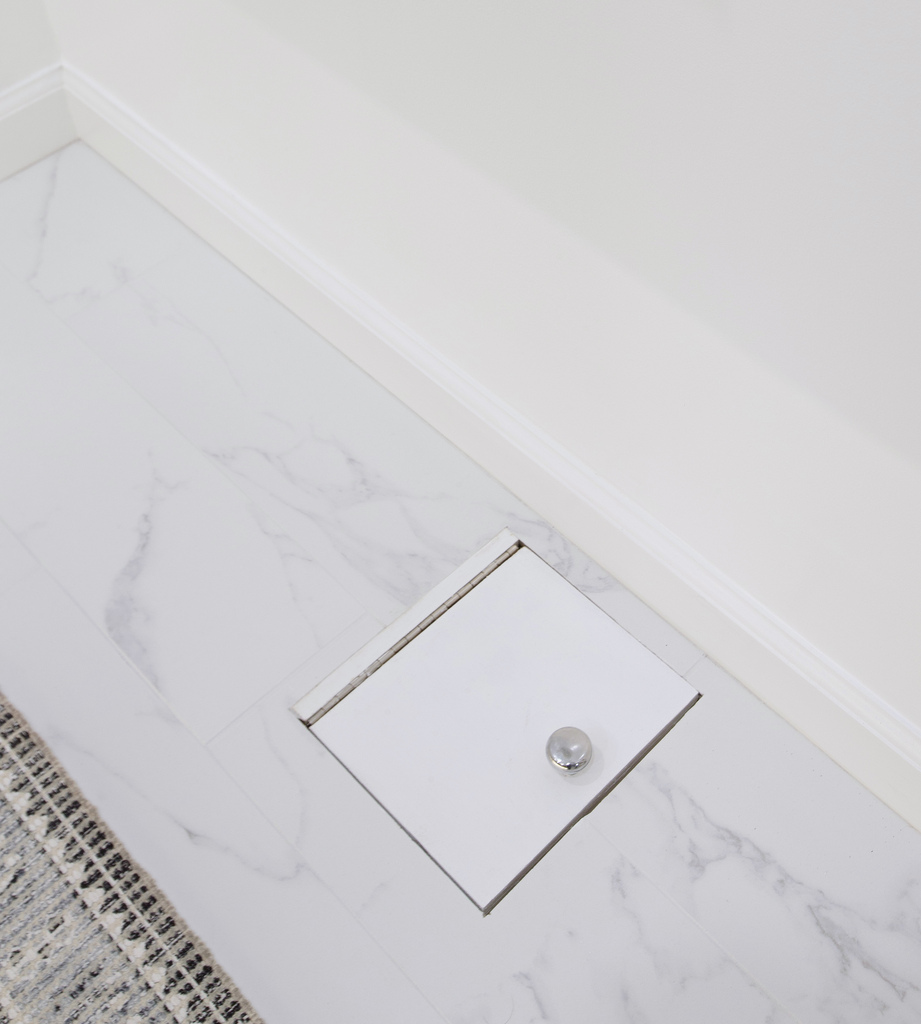 Vienna custom home detail shot of floor hatch access in marble-tiled bathroom by Anchor Remodel.
