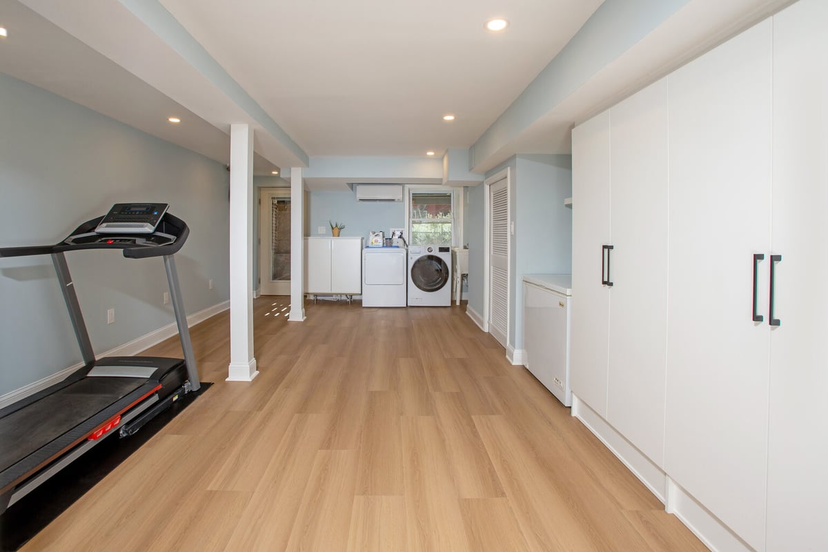 Full view of custom multifunctional basement with laundry, gym, and storage by Anchor Remodel in Springfield, VA.