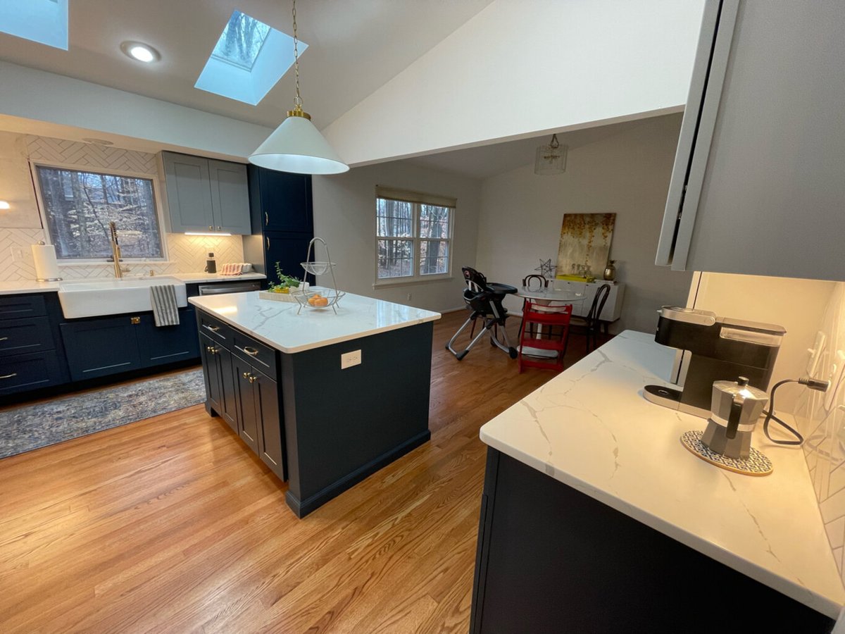 Open kitchen and dining layout with skylights and navy cabinetry in Springfield custom home by Anchor Remodel.