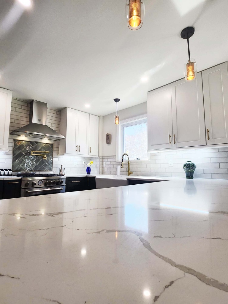 Close-up of quartz island and modern pendant lights in kitchen by Anchor Remodel in Alexandria, VA