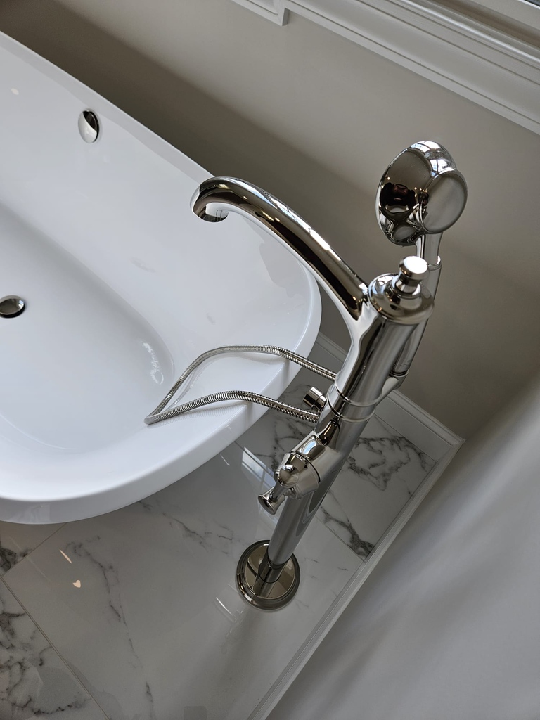 Freestanding tub with modern chrome floor-mounted faucet in Leesburg bathroom by Anchor Remodel.