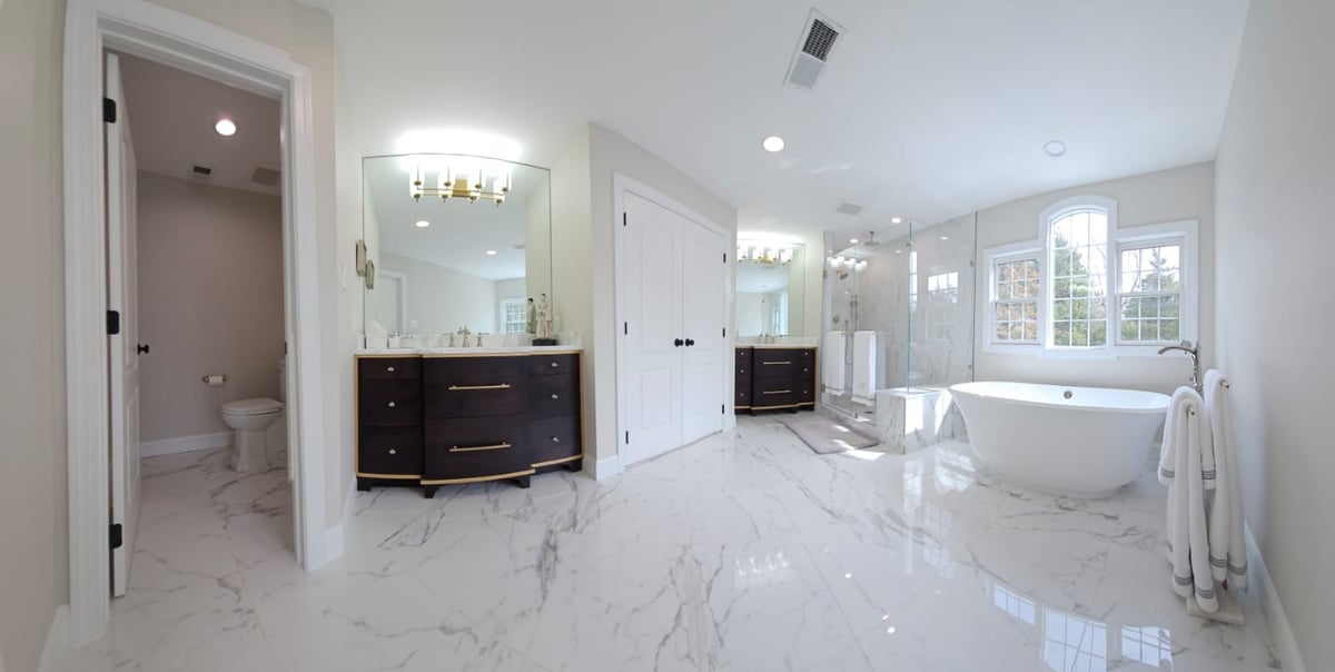 Full view of luxury bathroom remodel in Leesburg featuring marble tile and custom cabinetry by Anchor Remodel.