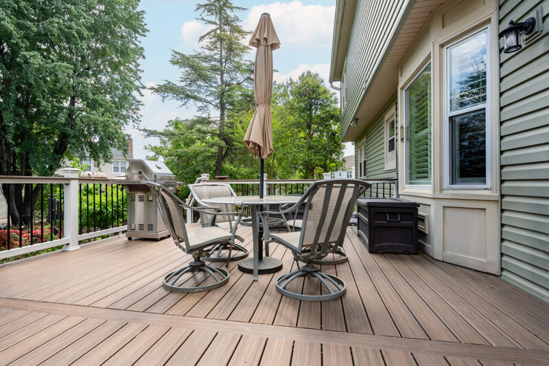Custom Trex composite deck remodel in Alexandria, VA with outdoor dining furniture, patio umbrella, and stainless steel grill.