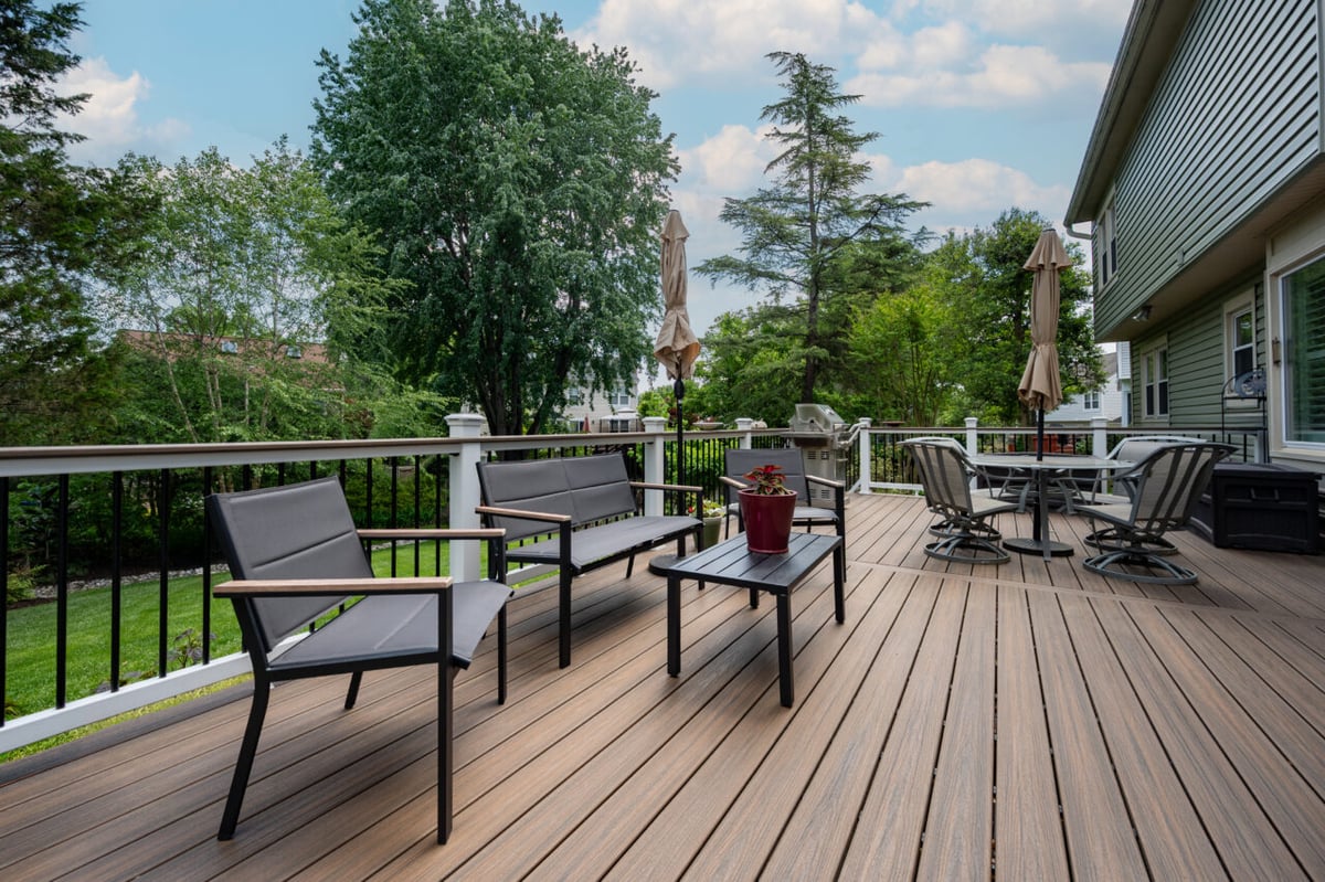Backyard entertainment deck in Alexandria, VA with Trex composite decking, lounge seating, dining table, grilling area, and durable low-maintenance materials.