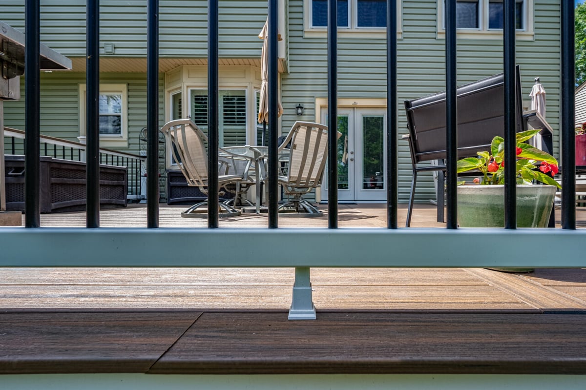 View through black aluminum deck railing showcasing Trex composite decking and outdoor dining area in Alexandria, VA.
