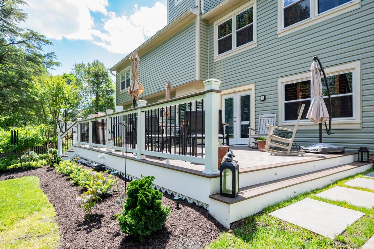 Custom deck remodel in Alexandria, VA featuring Trex composite decking, black baluster railing, and integrated landscape design.