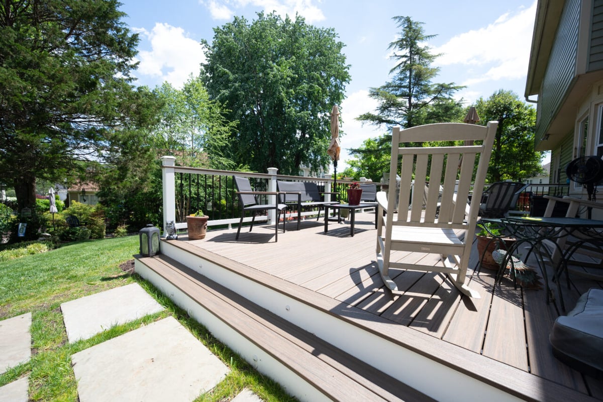 A view from the paver path stepping up to the relaxation area on a deck in Alexandria, VA with Trex composite decking, rocking chair, lounge seating, and backyard views.