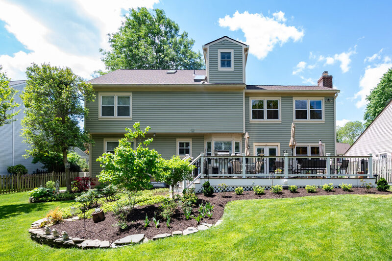 Wide backyard view of a deck remodel in Alexandria, VA featuring Trex composite decking, black railing, and lush landscaping.