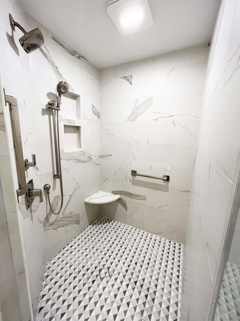 Accessible walk-in shower design with handheld showerhead and seat by Anchor Remodel in McLean, VA.