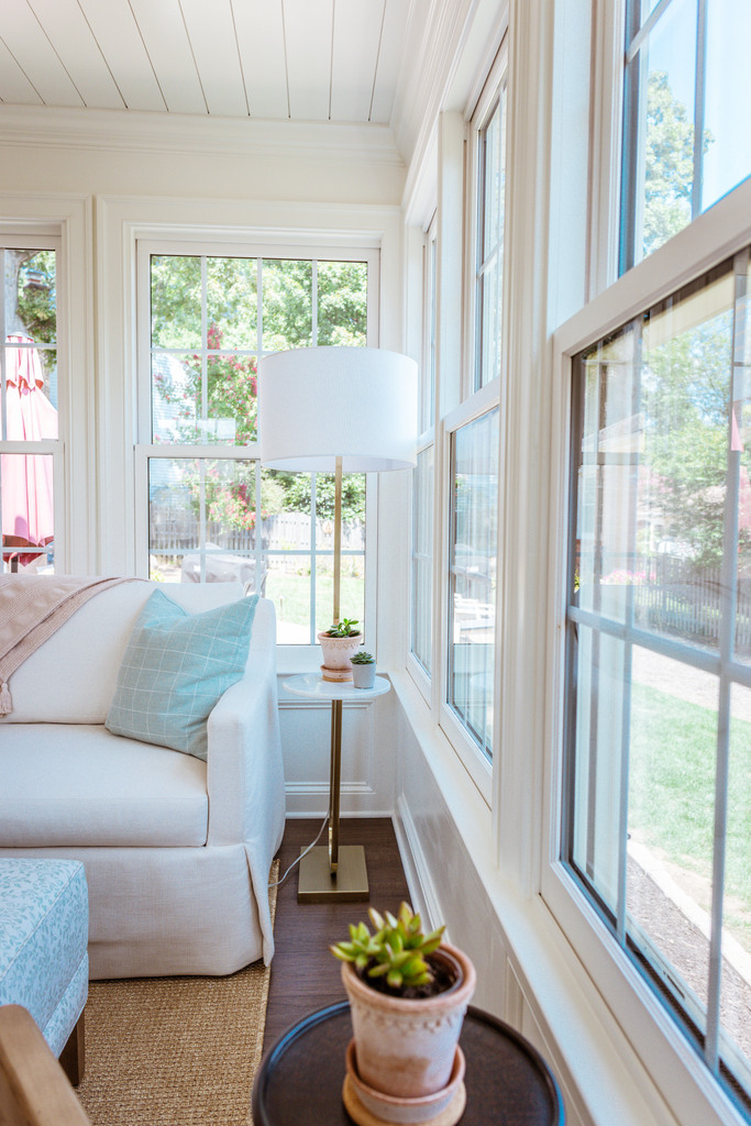 Window-lined corner of custom sunroom with sofa and floor lamp by Anchor Remodel in Alexandria, VA